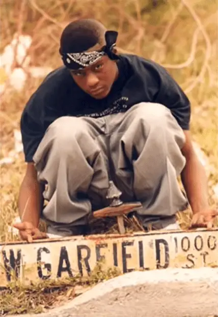 A person squatting down next to a signDescription automatically generated with low confidence